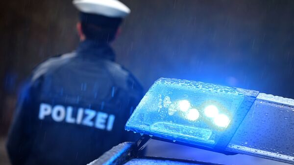 Ein Polizist steht im Regen vor einem Streifenwagen., © Karl-Josef Hildenbrand/dpa/Symbolbild