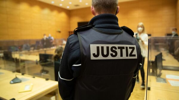 Ein Justizbeamter steht in einem Gerichtssaal., © Friso Gentsch/dpa/Symbolbild