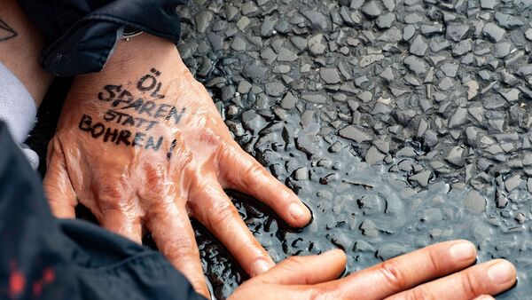 «Öl sparen statt bohren» steht auf der Hand einer Demonstrantin der Gruppe «Letzte Generation»., © Paul Zinken/dpa/Symbolbild