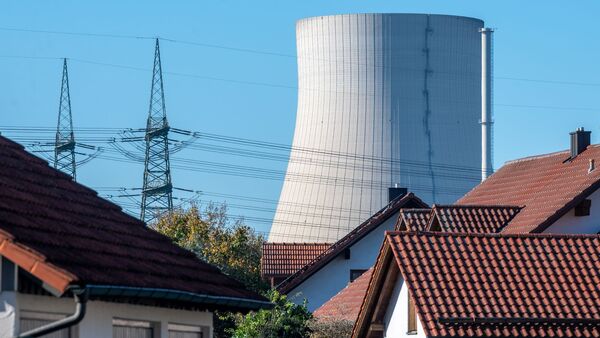 Der Kühlturm des Kernkraftwerks Isar 2. ist hinter Häusern von Niederaichbach zu sehen., © Armin Weigel/dpa/Archivbild
