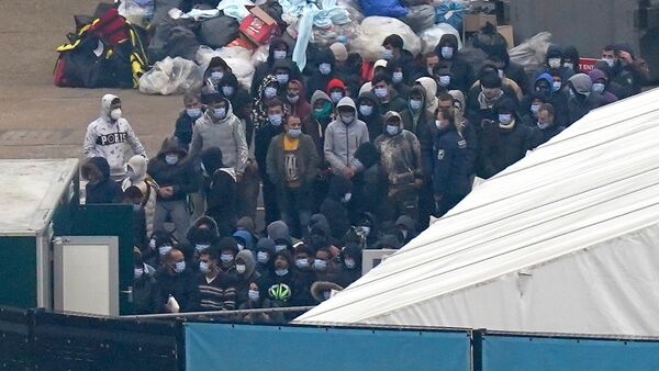 Eine Gruppe von Personen, bei denen es sich vermutlich um Migranten handelt, wartet auf ihre Registrierung in Dover., © Gareth Fuller/PA Wire/dpa