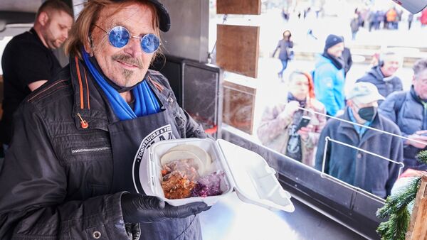Frank Zander steht im Caritas-Foodtruck und verteilt warme Mahlzeiten an Obdachlose und bedürftige Menschen auf dem Alexanderplatz in Berlin., © Annette Riedl/dpa