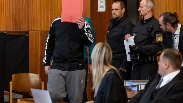 Ein wegen Mordes angeklagter Mann (l) trifft zum Prozessbeginn in der Stadthalle ein., © Daniel Karmann/dpa